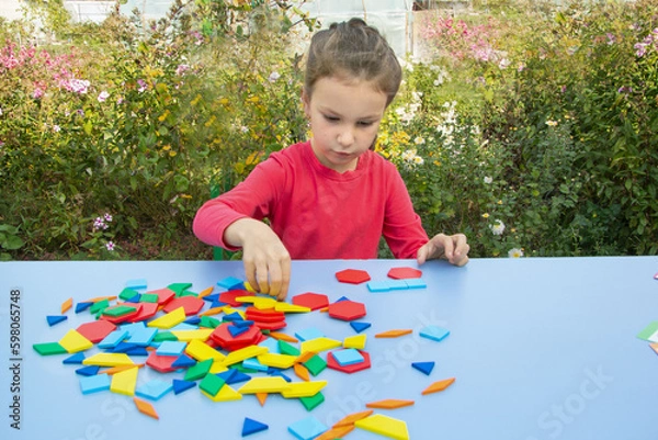 Fototapeta A girl plays with the figures of a constructor on the street