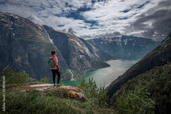 Fototapeta Girl standing on top of Eidfjord in Norway, looking over the fjord and mountains