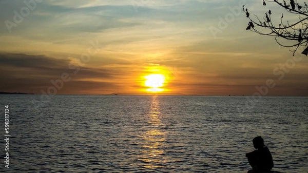 Obraz A kid sits on the beach during sunset in Lombok Island, Indonesia