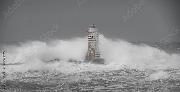 Fototapeta Lighthouse and storm - The Mangiabarche rock of Calasetta during the February 2023 storm
