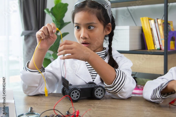 Fototapeta School student making robotic cars. Girl at robotics school makes robot managed from the constructor, child learns robot constructing.
