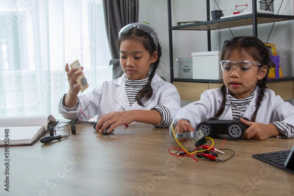 Obraz School student making robotic cars. Girl at robotics school makes robot managed from the constructor, child learns robot constructing.