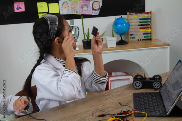Fototapeta School student making robotic cars. Girl at robotics school makes robot managed from the constructor, child learns robot constructing.