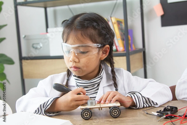 Fototapeta School student making robotic cars. Girl at robotics school makes robot managed from the constructor, child learns robot constructing.