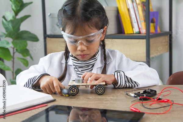 Obraz School student making robotic cars. Girl at robotics school makes robot managed from the constructor, child learns robot constructing.