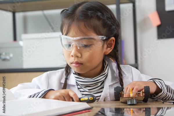 Fototapeta School student making robotic cars. Girl at robotics school makes robot managed from the constructor, child learns robot constructing.