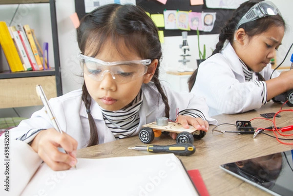 Fototapeta School student making robotic cars. Girl at robotics school makes robot managed from the constructor, child learns robot constructing.