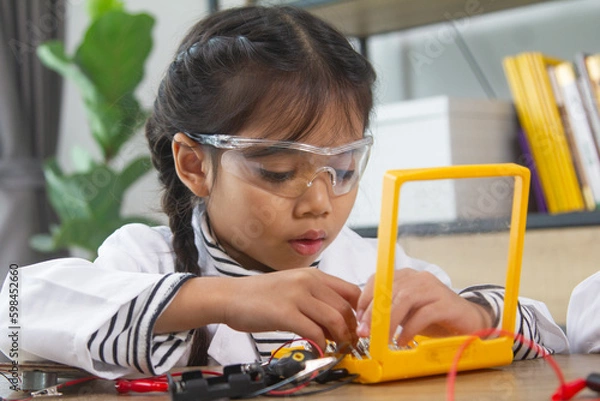 Obraz School student making robotic cars. Girl at robotics school makes robot managed from the constructor, child learns robot constructing.