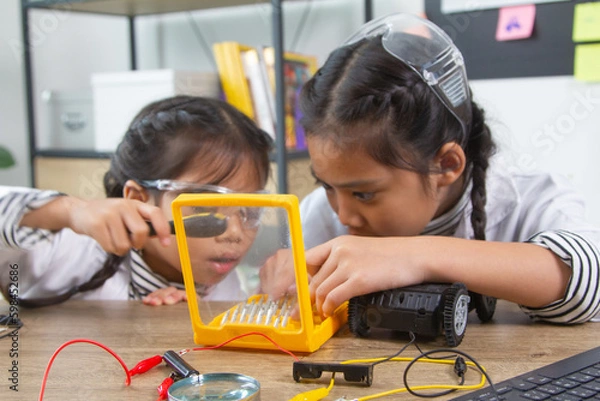 Fototapeta School student making robotic cars. Girl at robotics school makes robot managed from the constructor, child learns robot constructing.