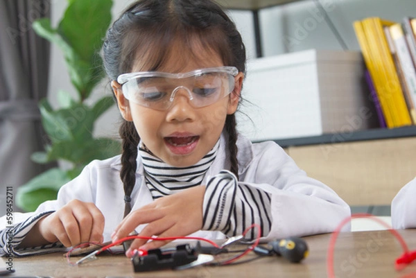 Fototapeta School student making robotic cars. Girl at robotics school makes robot managed from the constructor, child learns robot constructing.