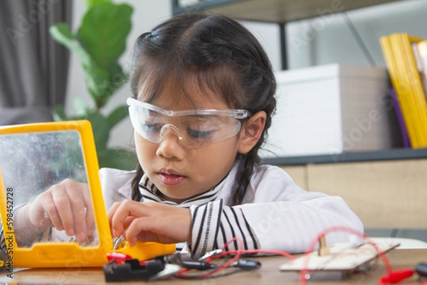 Fototapeta School student making robotic cars. Girl at robotics school makes robot managed from the constructor, child learns robot constructing.