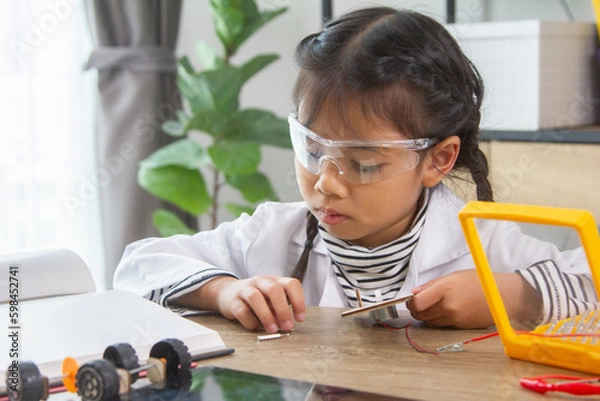 Fototapeta School student making robotic cars. Girl at robotics school makes robot managed from the constructor, child learns robot constructing.