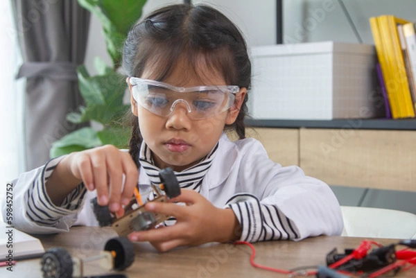 Fototapeta School student making robotic cars. Girl at robotics school makes robot managed from the constructor, child learns robot constructing.