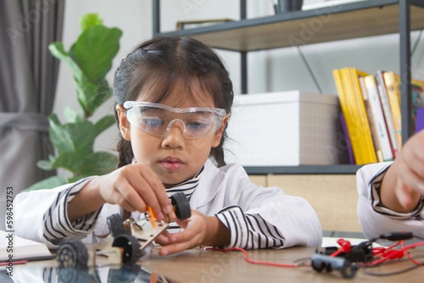 Obraz School student making robotic cars. Girl at robotics school makes robot managed from the constructor, child learns robot constructing.