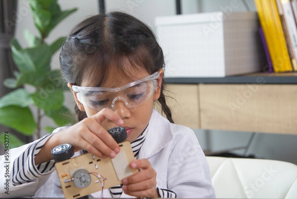Fototapeta School student making robotic cars. Girl at robotics school makes robot managed from the constructor, child learns robot constructing.