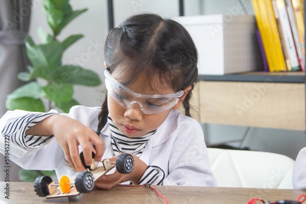 Obraz School student making robotic cars. Girl at robotics school makes robot managed from the constructor, child learns robot constructing.