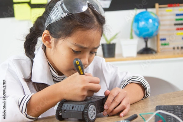 Fototapeta School student making robotic cars. Girl at robotics school makes robot managed from the constructor, child learns robot constructing.