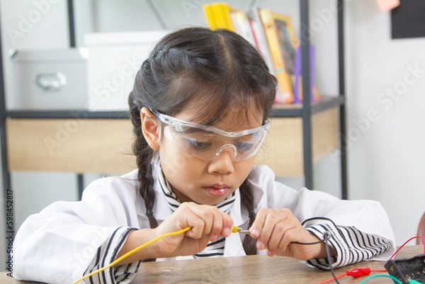 Fototapeta School student making robotic cars. Girl at robotics school makes robot managed from the constructor, child learns robot constructing.