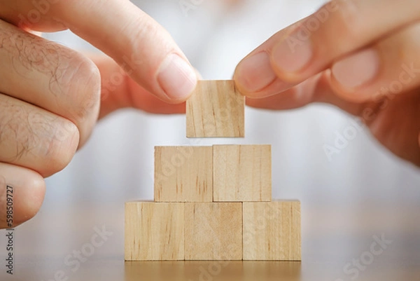 Obraz Close-up photo of putting wooden block on top of pyramid. Planning business growth. Horizontal concept with copy space for your text.