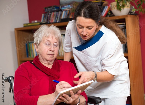Obraz nurse is helping a old woman with a form