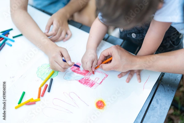 Fototapeta A family draws on paper lying on their free time on the table.