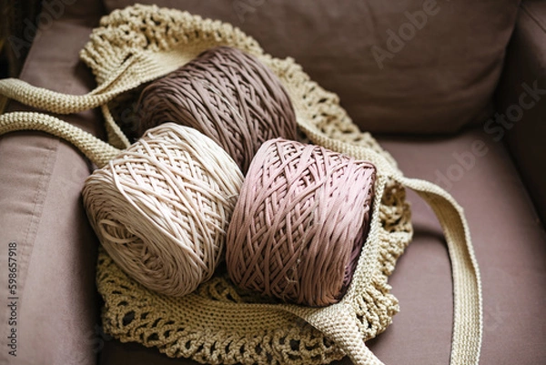 Obraz Three balls of knitted thread in an eco-friendly bag on a beige chair.