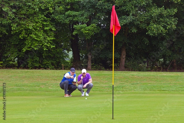 Obraz Golfer and caddy putting green.