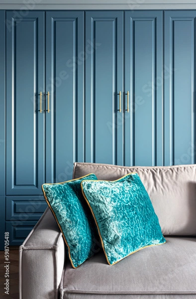 Fototapeta close-up of a gray sofa with a plaid and pillows against a blue panel wall