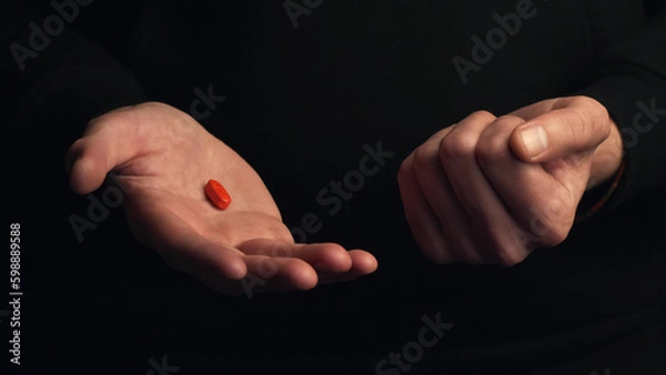 Obraz Studio shot hands show red pill isolated on black background. Concept of making right choice.