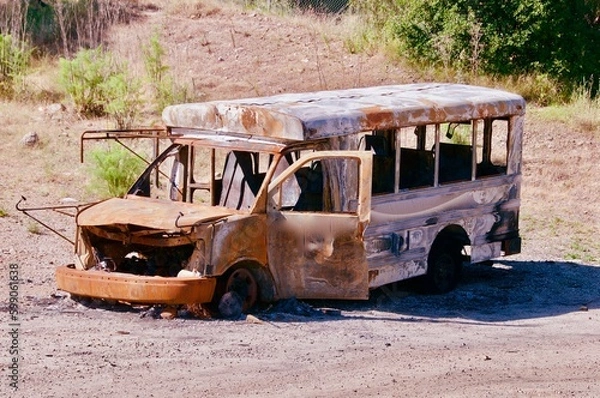 Obraz Old burned out rusted school bus sitting in vacant field