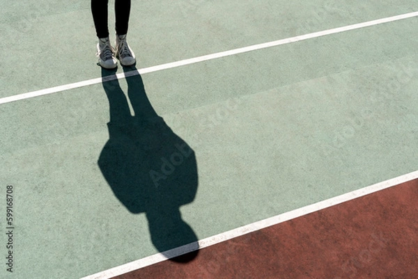 Obraz Girl standing on bright sun casting a long shadow