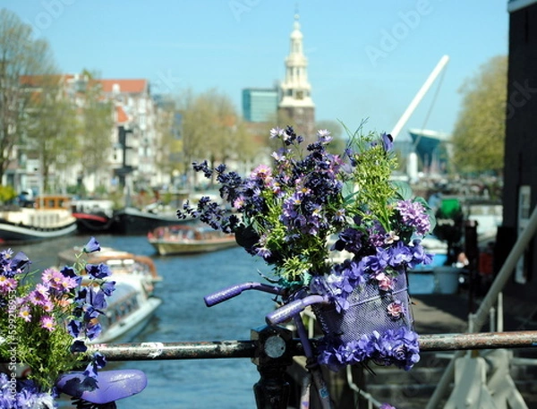 Fototapeta Bicycle trimmed with flowers on a bridge in the center of Amsterdam with in the background the Montelbaans tower built in 1516