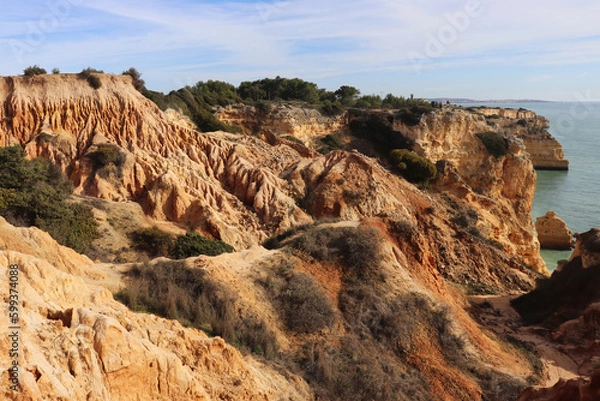 Fototapeta Orange limestone cliffs next to the Atlantic Ocean along the Seven Hanging Valleys hiking path in Algarve, Portugal.