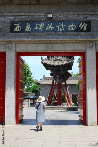Obraz XI'AN. CHINA.A woman in a hat passes through the red gate leading to the Cathedral mosque in XI'an. Old town. Xian. China.