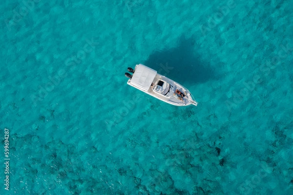 Obraz A yacht floating on the beautiful blue waters of Formentera, with a couple lying down and resting on board.