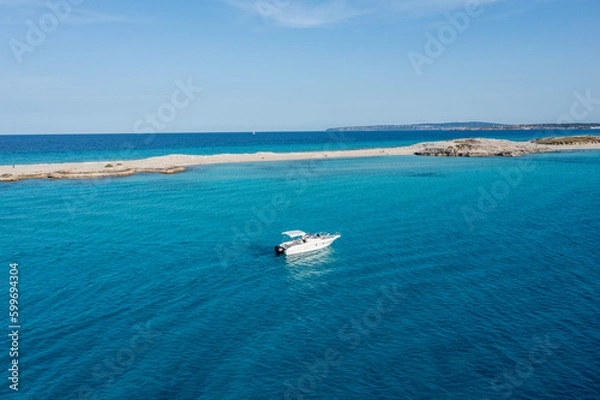 Fototapeta A yacht floating on the beautiful blue waters of Formentera, with a couple lying down and resting on board.