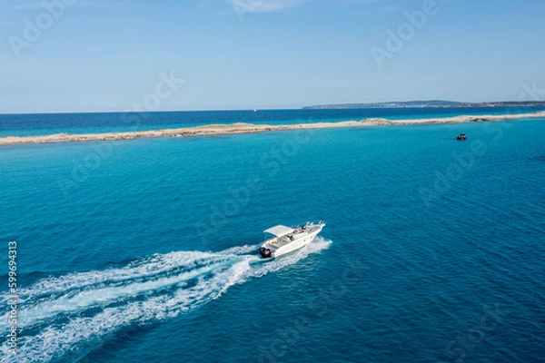 Obraz A yacht gliding through the beautiful blue waters of Formentera, with a couple on board enjoying the motion