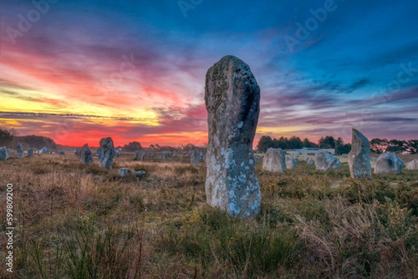 Fototapeta Alignement mégalithique, arrangement de menhirs au lever du soleil Carnac, Bretagne, France