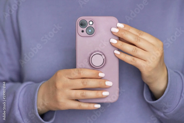Fototapeta Puple silicone case with ring on new mobile phone in female hands. Faceless woman make a photo on smartphone. Monochrome concept