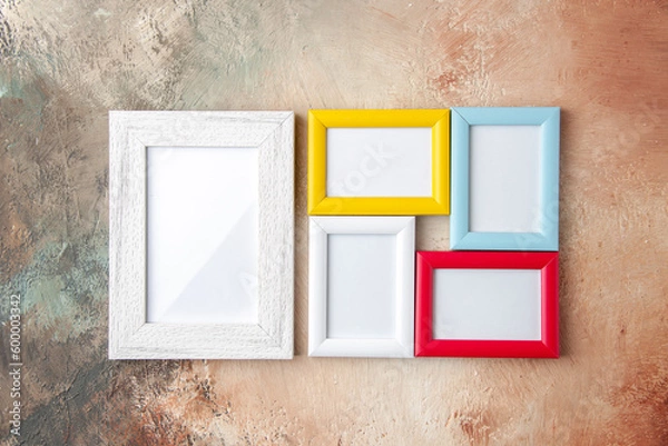Fototapeta Top view of small and big colorful picture frames hanging on nude color wall with free space