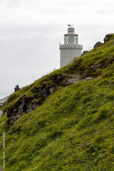 Fototapeta Lighthouse with down and hillside against a plane sky