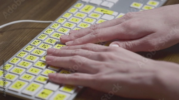 Fototapeta Close-up of a computer keyboard with braille. A blind girl is typing words on the buttons with her hands. Technological device for visually impaired people