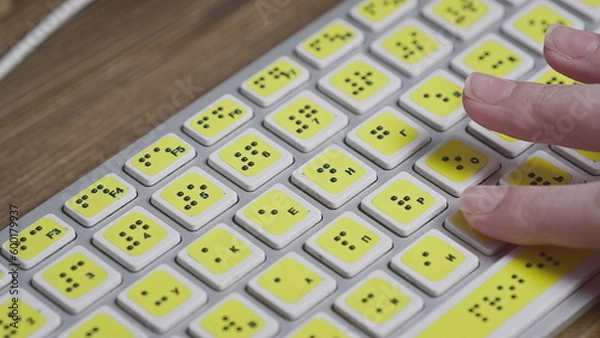 Fototapeta Close-up of a computer keyboard with braille. A blind girl is typing words on the buttons with her hands. Technological device for visually impaired people.