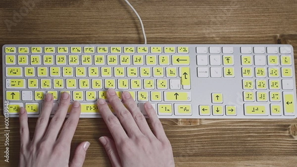 Fototapeta Close-up of a computer keyboard with braille. A blind girl is typing words on the buttons with her hands. Technological device for visually impaired people.
