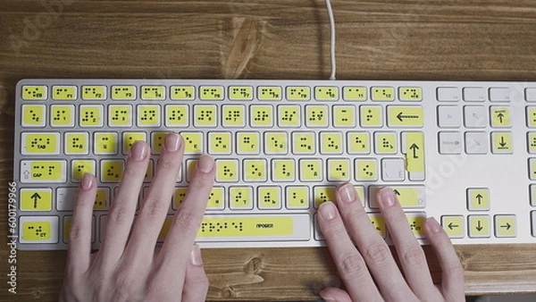 Obraz Close-up of a computer keyboard with braille. A blind girl is typing words on the buttons with her hands. Technological device for visually impaired people.