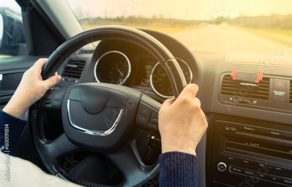 Fototapeta Driving with a car . View from car inside. Multi steering wheel with woman hands