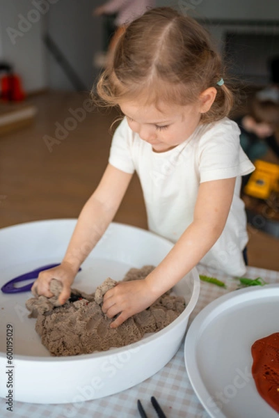 Fototapeta Little girl playing with kinetic sand and toys insect. Sensory development and experiences, themed activities with children, fine motor skills development