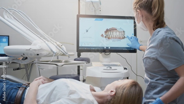Obraz Girl doctor dentist demonstrates a 3D model of teeth on a touch monitor. Dental consultation in the clinic, diagnostics