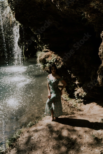 Obraz Beautiful model in a turquoise dress posing near a mountain waterfall.Wildlife concept