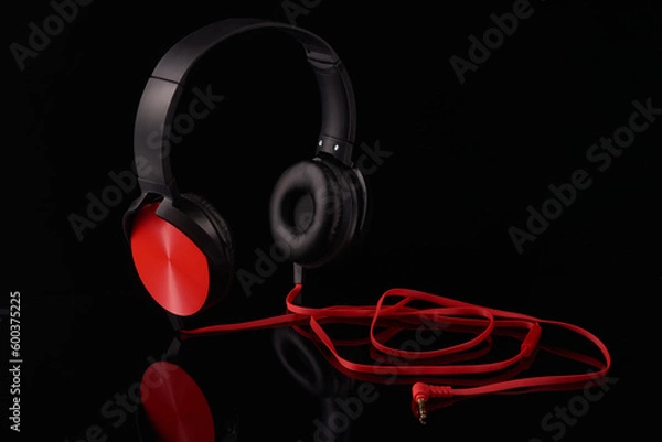 Fototapeta Black headphones with red inserts and a red wire on a black background,